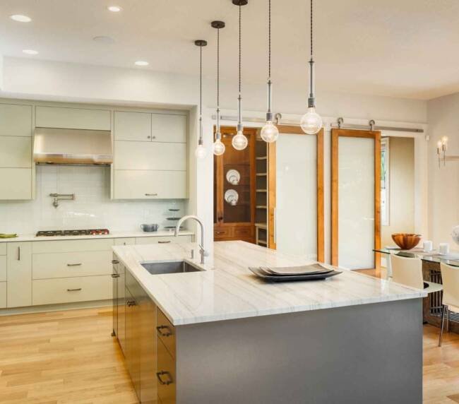 Modern condo kitchen with white cabinets and marble island, showcasing renovation potential for the question "Can you renovate a condo?"