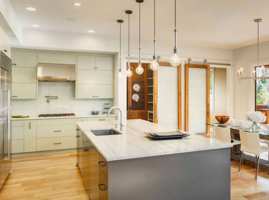 Modern condo kitchen with white cabinets and marble island, showcasing renovation potential for the question "Can you renovate a condo?"