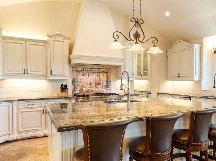 Luxurious kitchen with white cabinets and granite island, showcasing kitchen renovation financing potential.