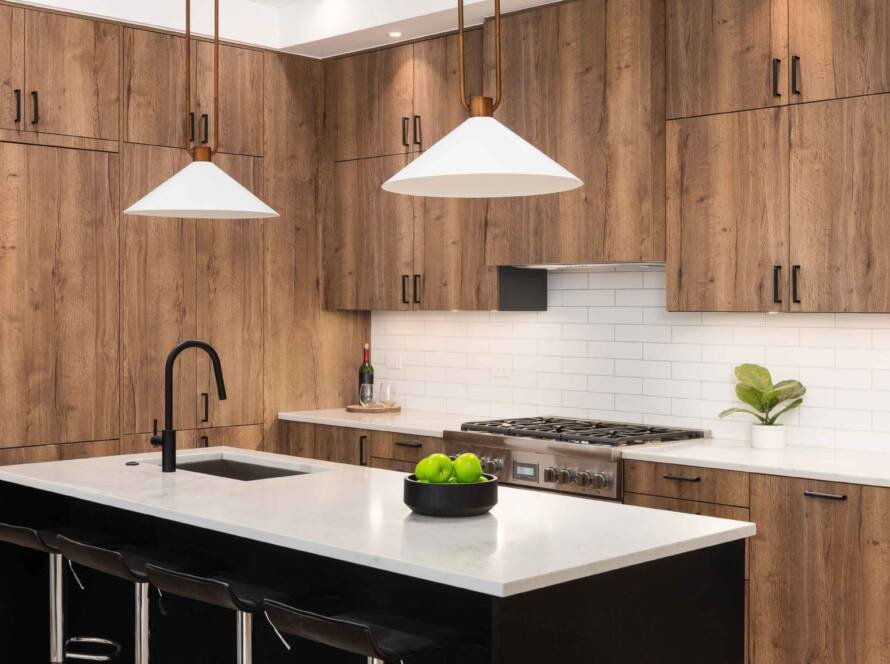 Modern kitchen island remodel with a white quartz countertop, black sink, and wooden cabinets. Features sleek bar stools, pendant lights, and a gas range in a stylish Dallas kitchen setup