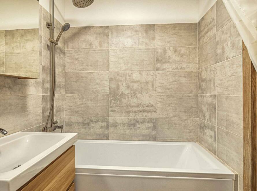 Modern bathroom with a sink, bathtub, shower, and wooden accents showcasing a stylish yet cheap bathroom remodel.