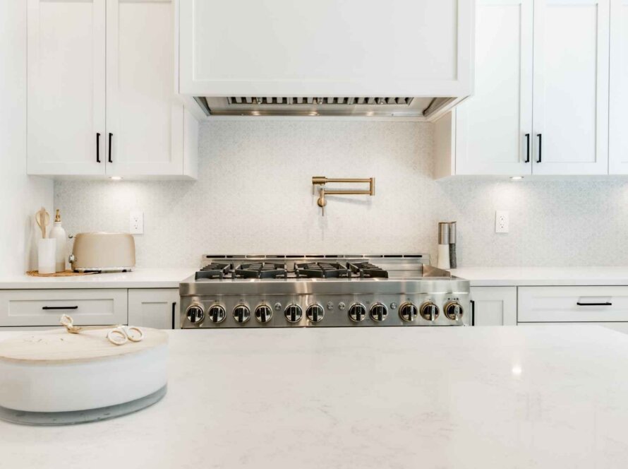 Modern kitchen with white cabinetry and appliances. Granite vs. Quartz