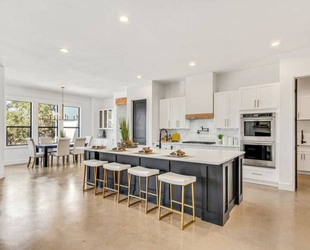 Modern open-concept kitchen with white cabinetry, a central island, and gold-accented bar stools crafted through expert kitchen remodeling Dallas services.