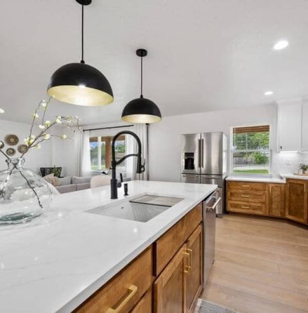 Modern kitchen with an open-concept design, marble countertop island, and wooden cabinetry with gold accents designed through kitchen remodeling Dallas services.